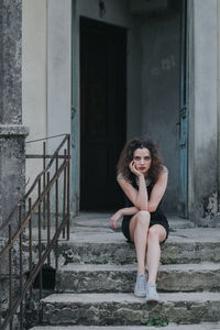 Portrait of woman standing on staircase against building