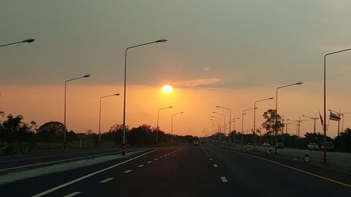 Cars on street against sky during sunset