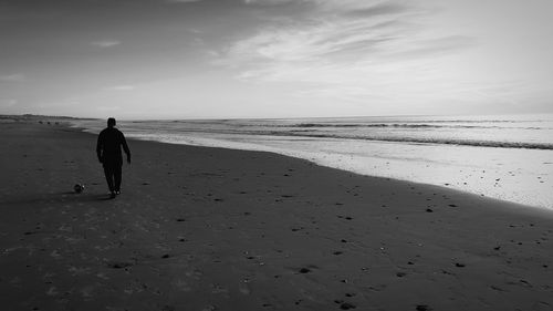 Rear view of woman on beach against sky