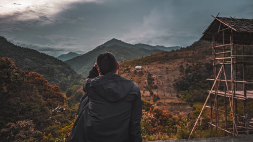 Rear view of man looking at mountains against sky