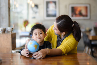 Mother and son with globe sitting at desk