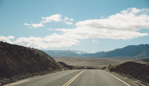 Road by mountains against sky