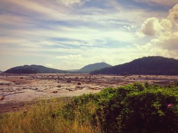 Scenic view of land and mountains against sky