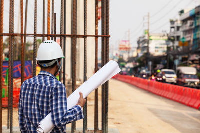 Man holding umbrella while standing at construction site