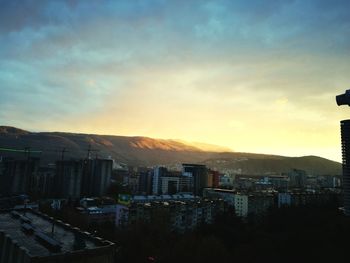 Cityscape by sea against sky during sunset