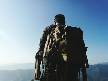 Rear view of man with backpack standing against mountains