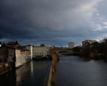 River amidst buildings in city against sky