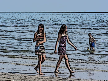 Low section of women standing on beach against sky