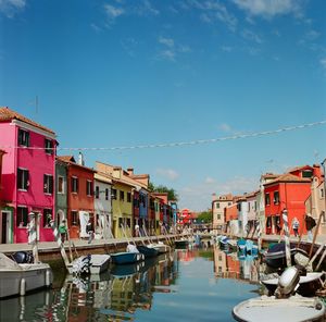 Boats moored in canal by buildings in city against sky