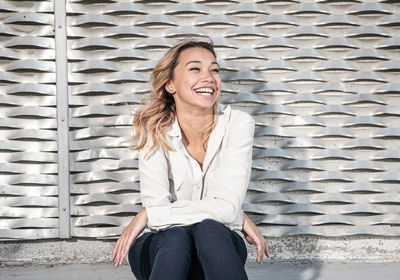 Portrait of a young woman with big smile in front of metallic wall