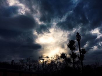 Silhouette of trees against cloudy sky