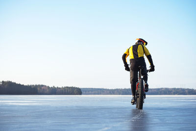 Man riding bicycle on snow against sky