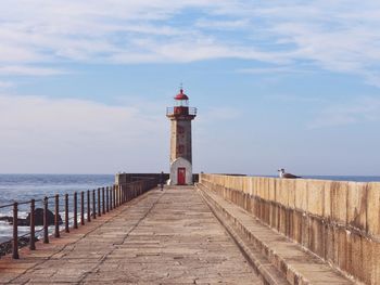 Lighthouse by sea against sky