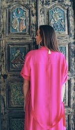 Rear view of woman standing against pink wall