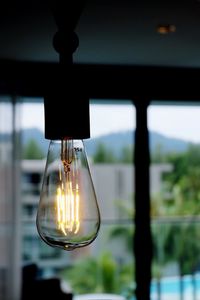 Close-up of illuminated light bulb against window