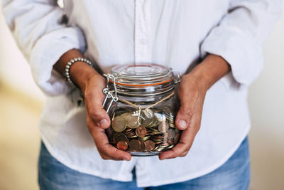 Midsection of man holding glass jar