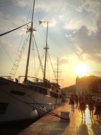 People at harbor against sky during sunset