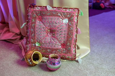 Close-up of cushion and antique containers on floor during wedding