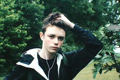 Portrait of boy with hand in hair against trees