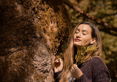 Portrait of young woman looking at tree