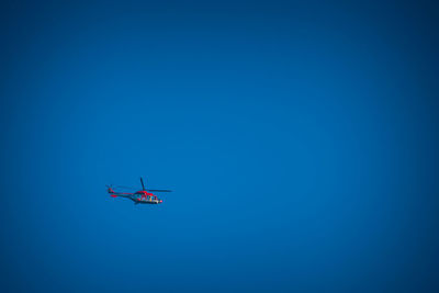 Low angle view of airplane flying against clear blue sky