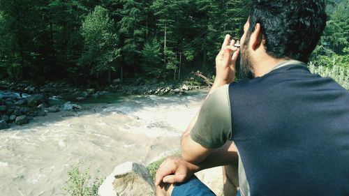 Rear view of man sitting at riverbank