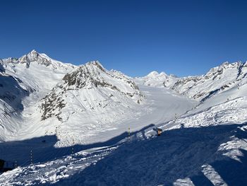 Scenic view of snowcapped mountains against clear blue sky