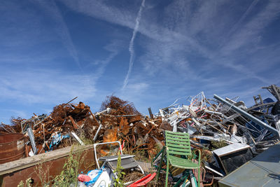 A vast heap of discarded appliances, furniture, and metal clutter lies in an open junkyard.