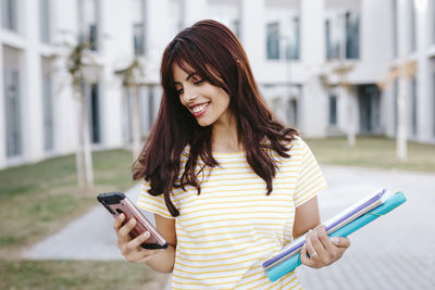 Smiling young woman using mobile phone