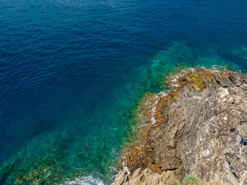 Aerial view of turquoise sea waves hitting rocks. amazing rock cliff seascape in the italian coast
