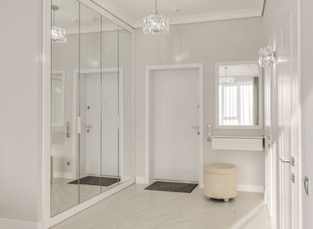 Bright entrance hall in a modern monotonous interior with a large mirrored wardrobe and sun rays