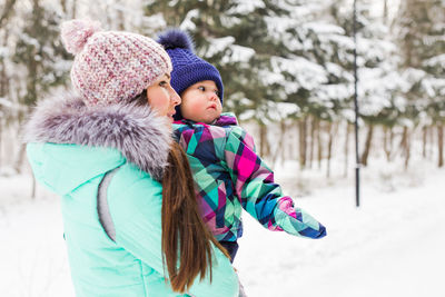 Portrait of smiling woman standing on snow covered field