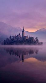 Reflection of statue on mountain against sky during sunset