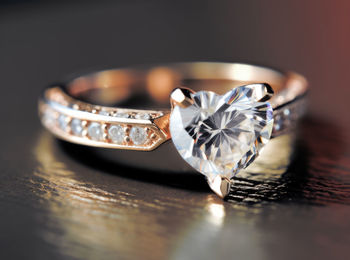 Golden ring with diamond in the shape of heart with reflection