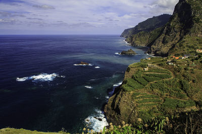 Scenic view of sea by mountains against sky