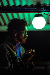 Side view of young man looking away at night