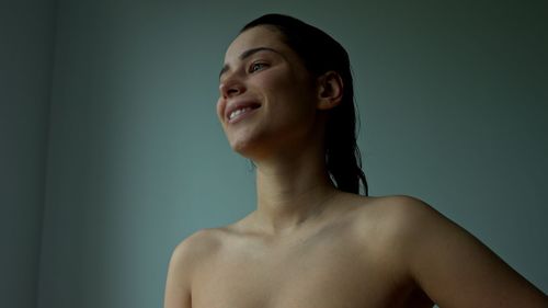 Portrait of smiling young woman looking away against blue background