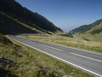 Scenic view of road by mountains against clear sky