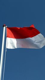 Low angle view of flag against clear blue sky