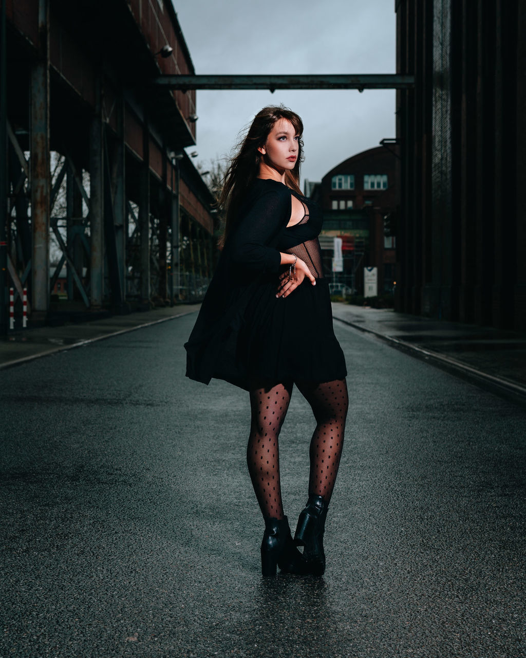 PORTRAIT OF YOUNG WOMAN LOOKING AWAY WHILE STANDING AGAINST WALL