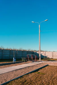 Street light on field against clear blue sky