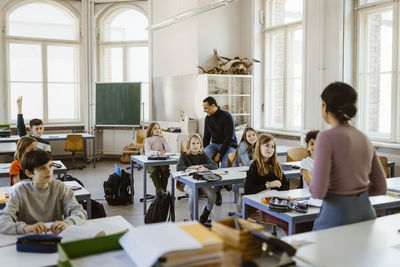 Male and female students listening to teacher teaching in classroom