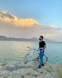 Man with bicycle on sea against sky