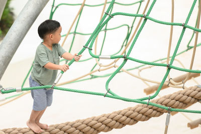 Full length of boy playing on rope
