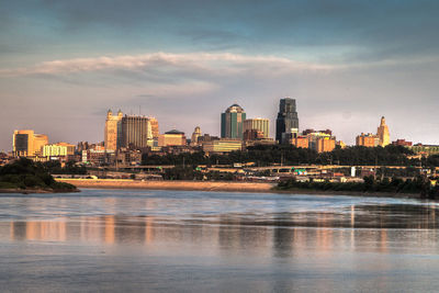 River in city against sky during sunset