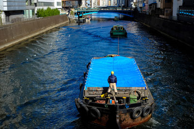 High angle view of man standing in ship on canal