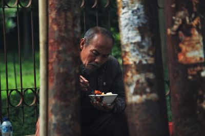 Side view of man eating food outdoors