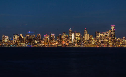 Illuminated cityscape against sky at night