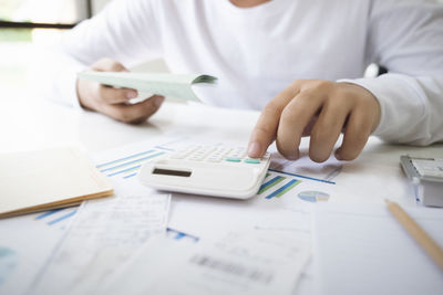 Midsection of man holding paper on table