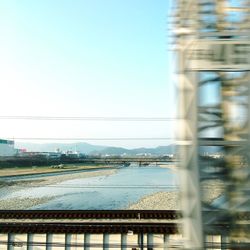 Railroad tracks by river against clear sky